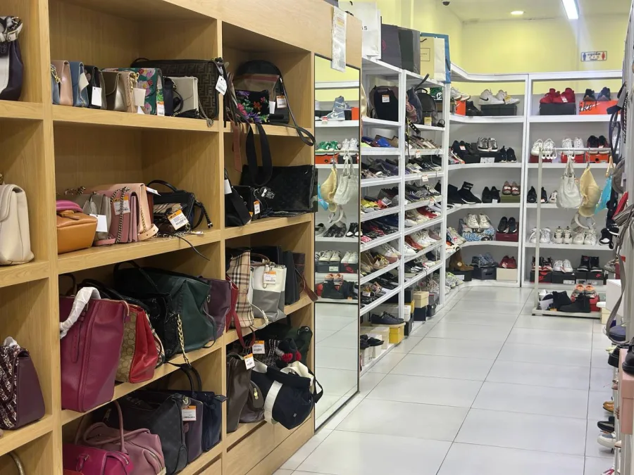 Aisle of shelved handbags and shoes with a fitting mirror